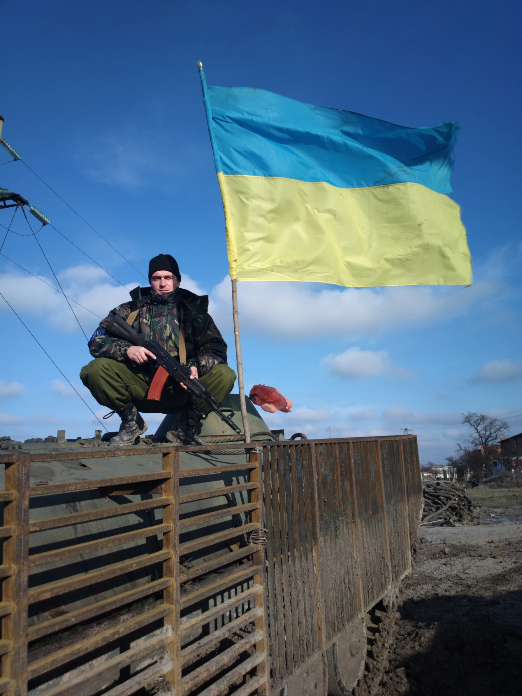 a man standing on a barricade with an ukraine flag flying in the air