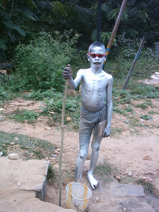 a boy in mud paint holding a metal pole