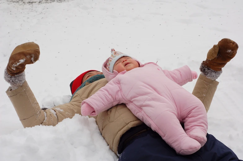 a young child laying in the snow wearing a hat