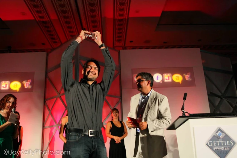 a man raising his hands at a podium during an awards night