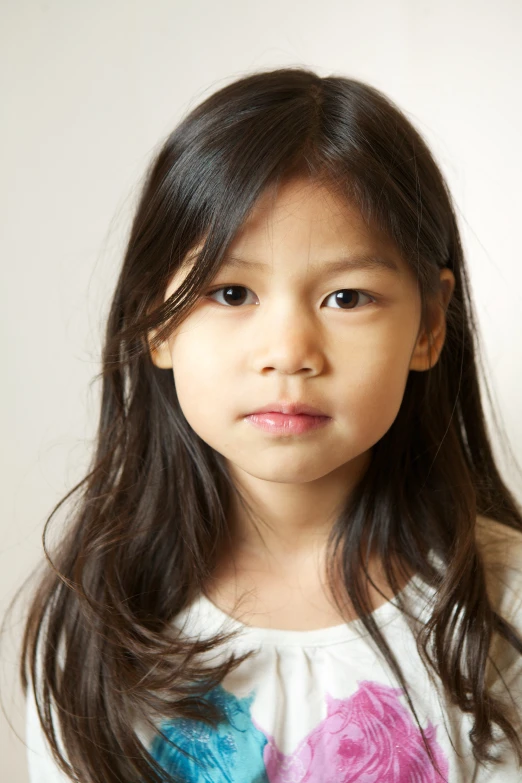 a little girl with long hair in a white t - shirt