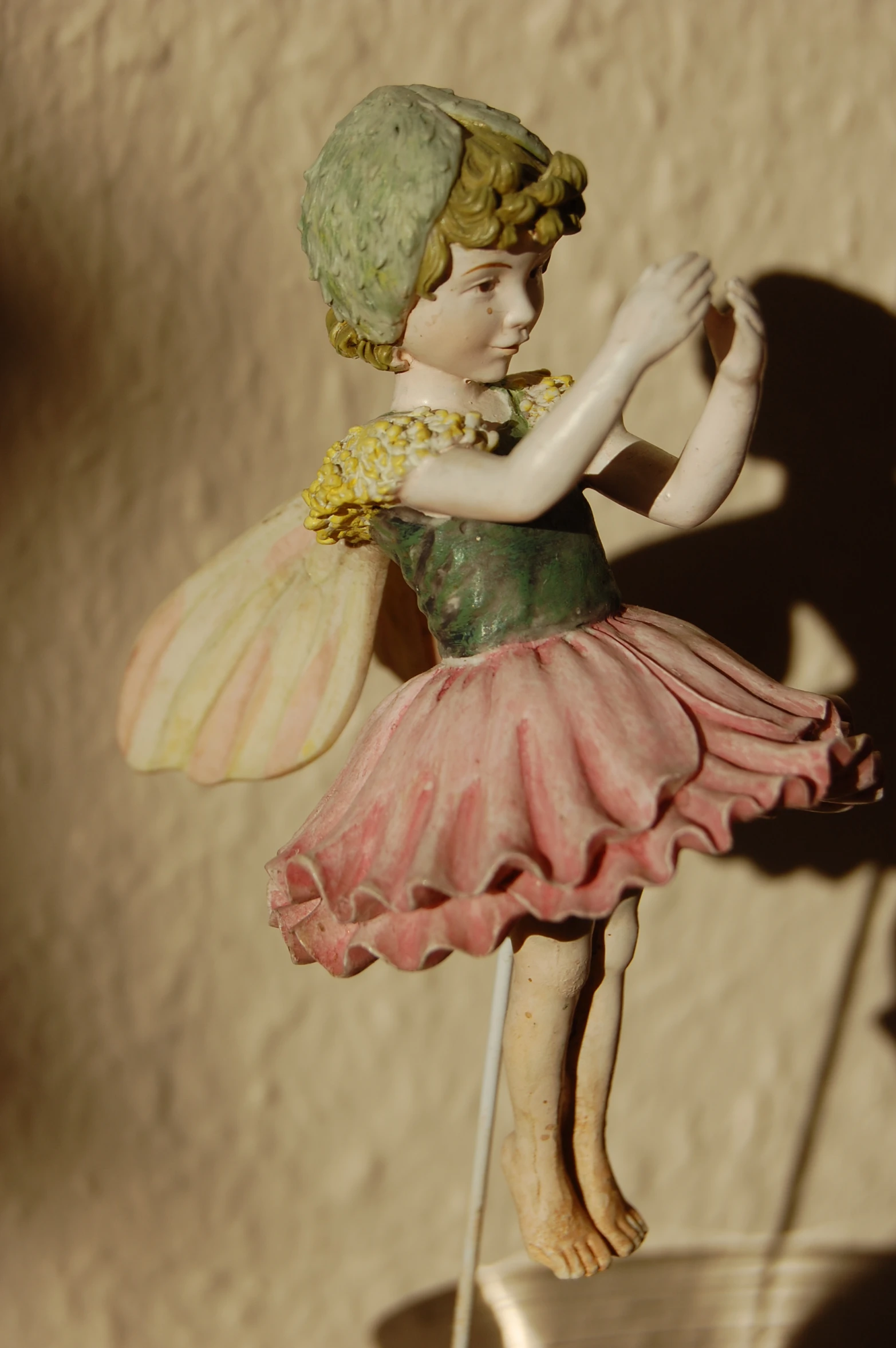 statue of fairy girl sitting on pedestal in front of wall