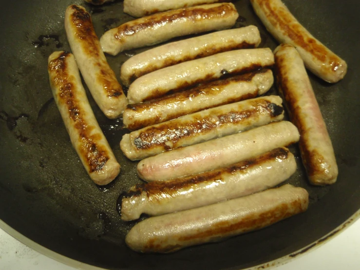 a pan with many sausages cooking in it