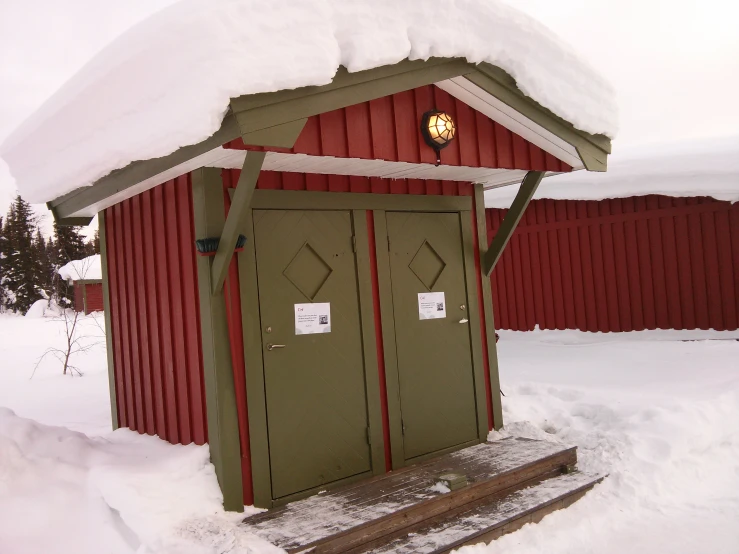 an old outhouse in winter is covered with snow