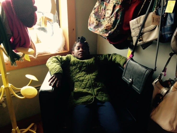 a woman sitting on a couch next to some handbags