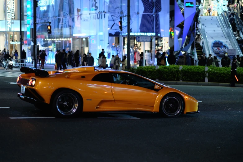 a sporty orange car is parked on the side of a road