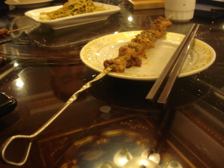 two white plates with chopsticks holding several food items