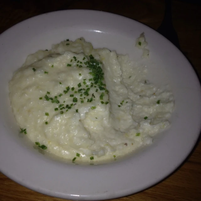 some mashed potatoes in a white bowl on a wooden table