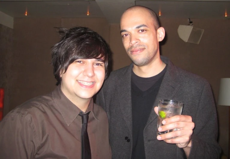 two men posing for the camera, one with a drink in his hand