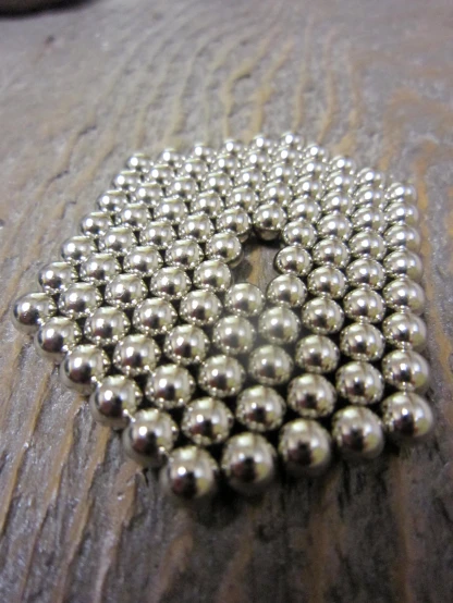 a metal object with little beads on a wooden surface