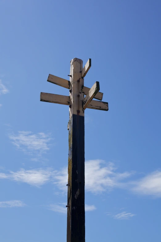 a wooden cross is shown against a clear blue sky