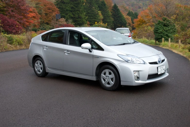a silver toyota prius parked on a street next to a hillside