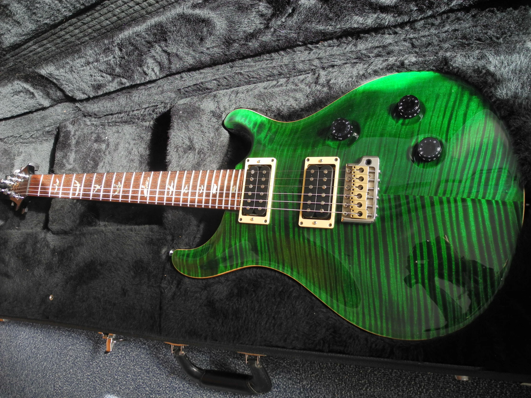 a green electric guitar sitting on display in a case