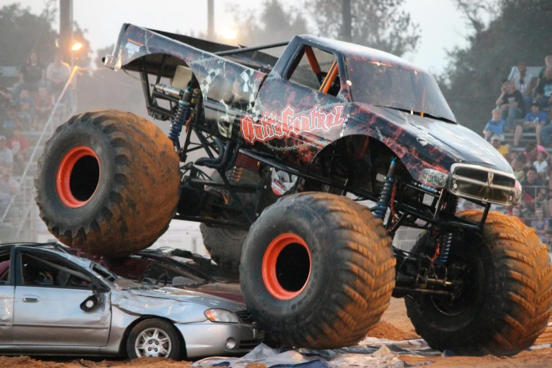 a truck is jumping over a car on a course