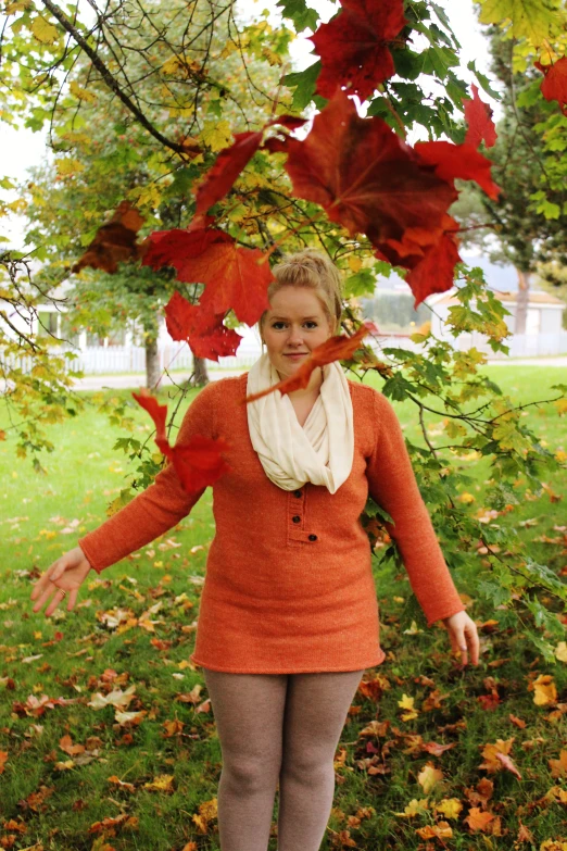 a woman standing next to many autumn leaves