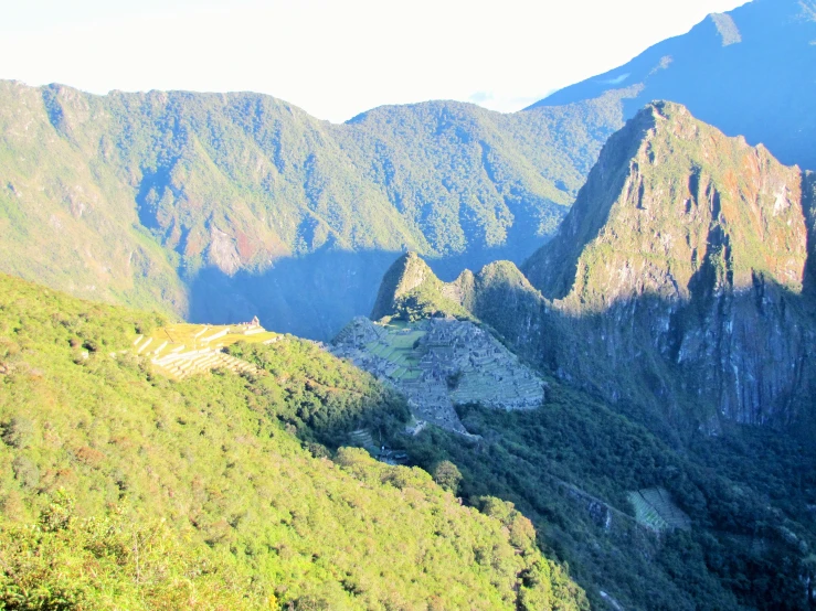 some green mountains and some trees with the sun shining