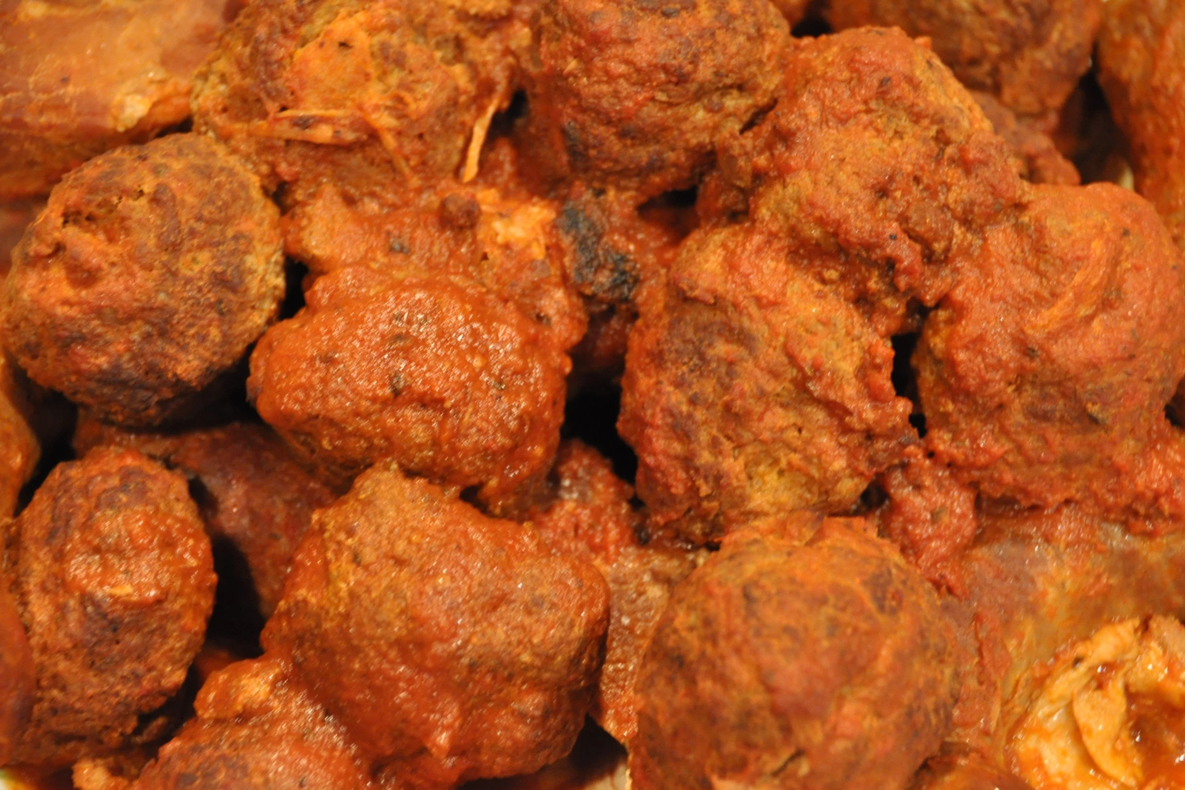 closeup of various meatballs with sauce