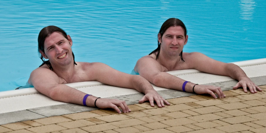 two men posing for a picture at a pool