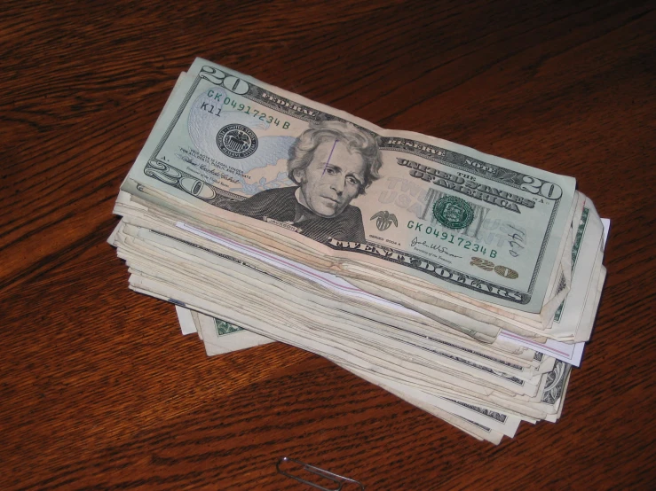 a stack of hundred dollars on top of a wooden table