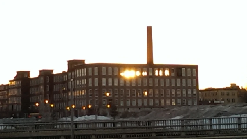 an old industrial building stands beside an icy waterway at dusk