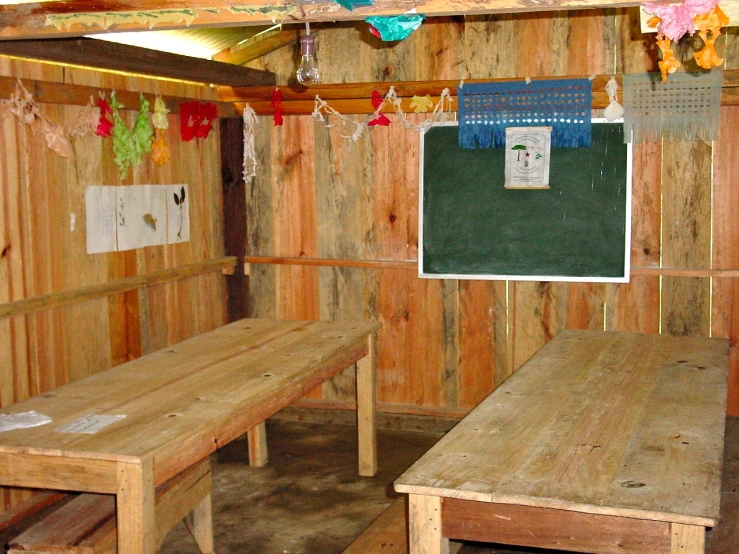 the inside of an outside area with tables, benches and green chalkboard