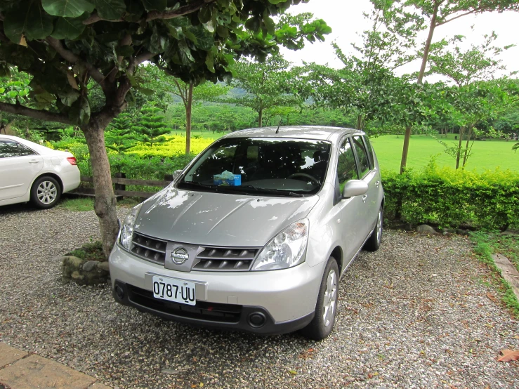 a small silver car parked beside another car on gravel