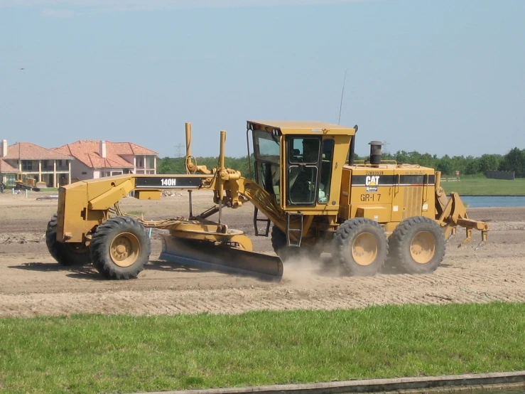 a yellow truck is shoveling dirt with a lawn