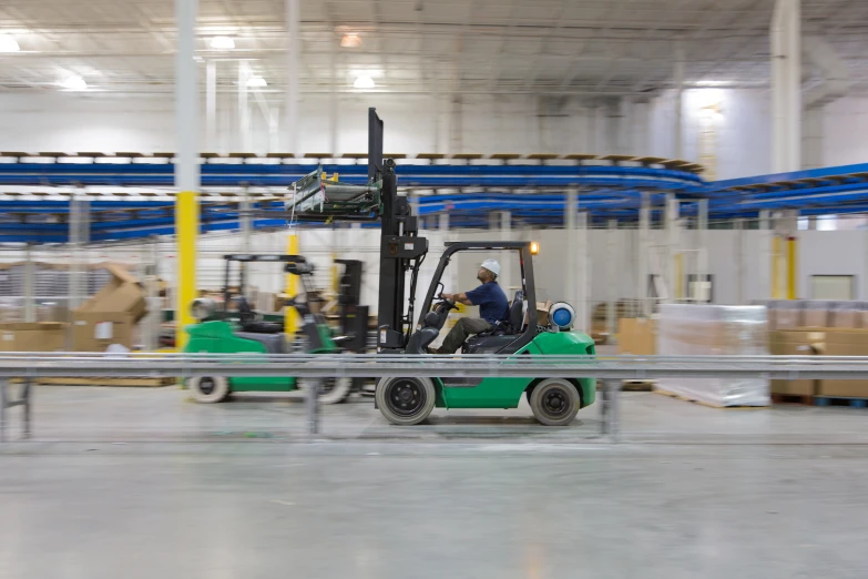 forklift moving inside a warehouse with a large amount of machinery in it