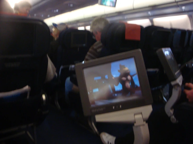 a television screen inside an airplane with seats
