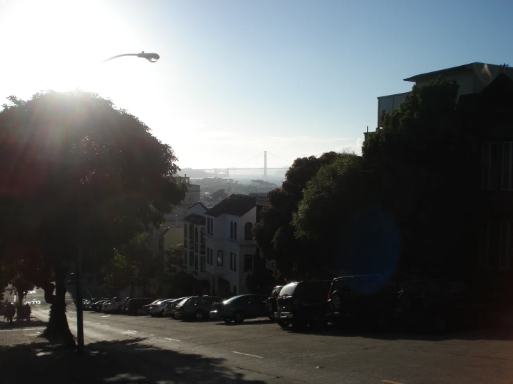 a street with parked cars and houses in the background