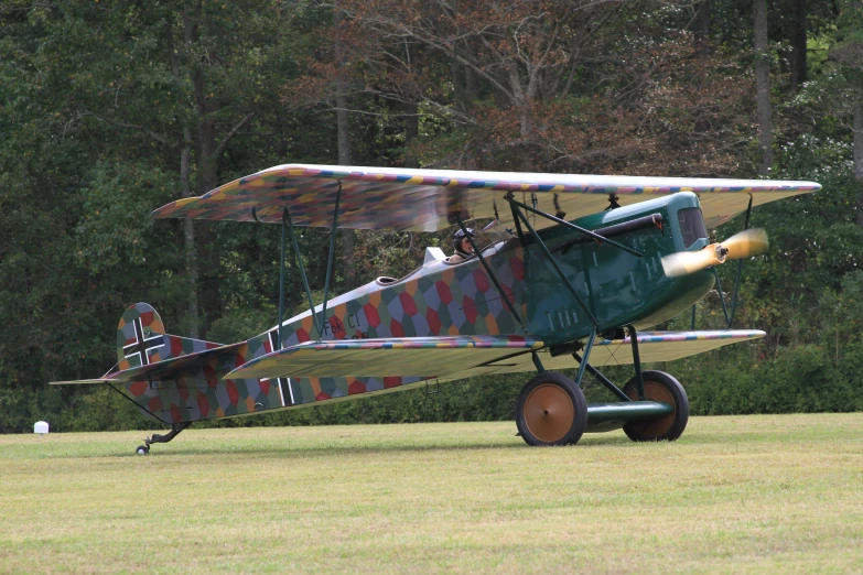 a plane sits in a field on wheels with grass and trees in the background