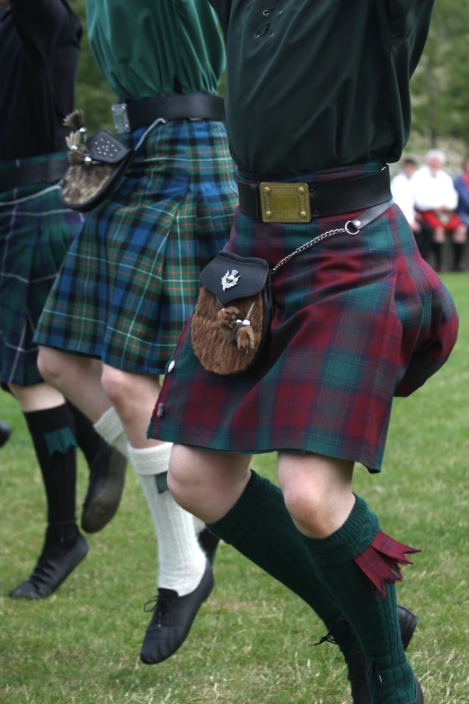 people in kilts are dancing on the grass