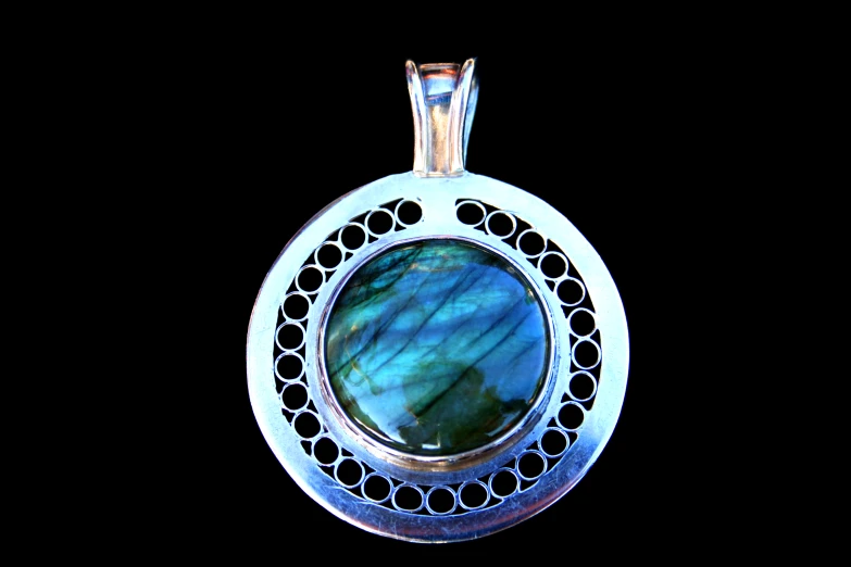 a silver pendant with green stone in the center