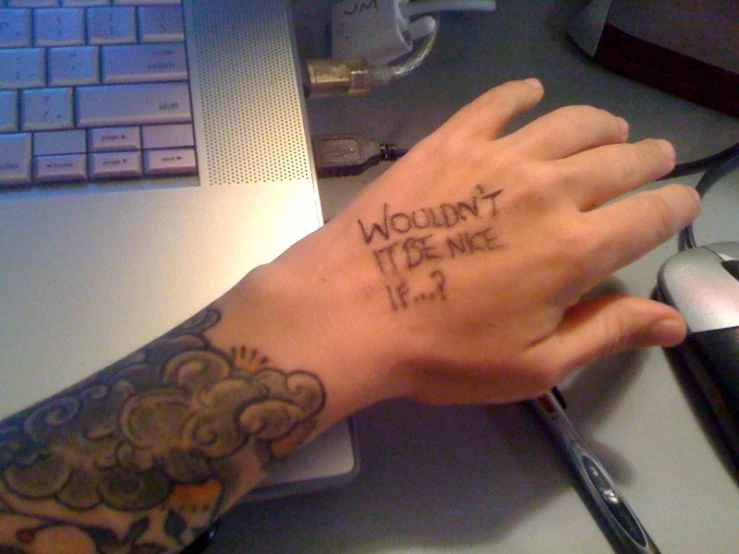 a person with tattoos on their wrist and a laptop