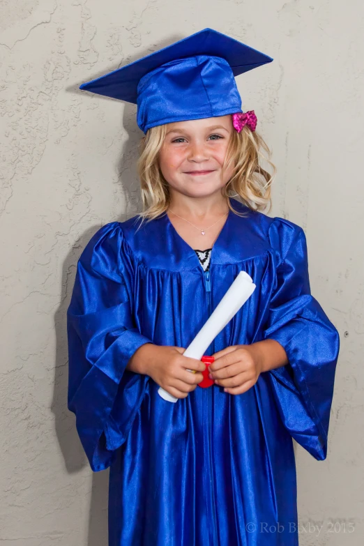 a girl in a graduation gown and cap holds her diploma
