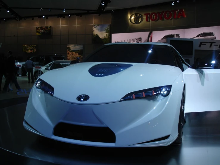 the front end of a white sports car parked in a showroom