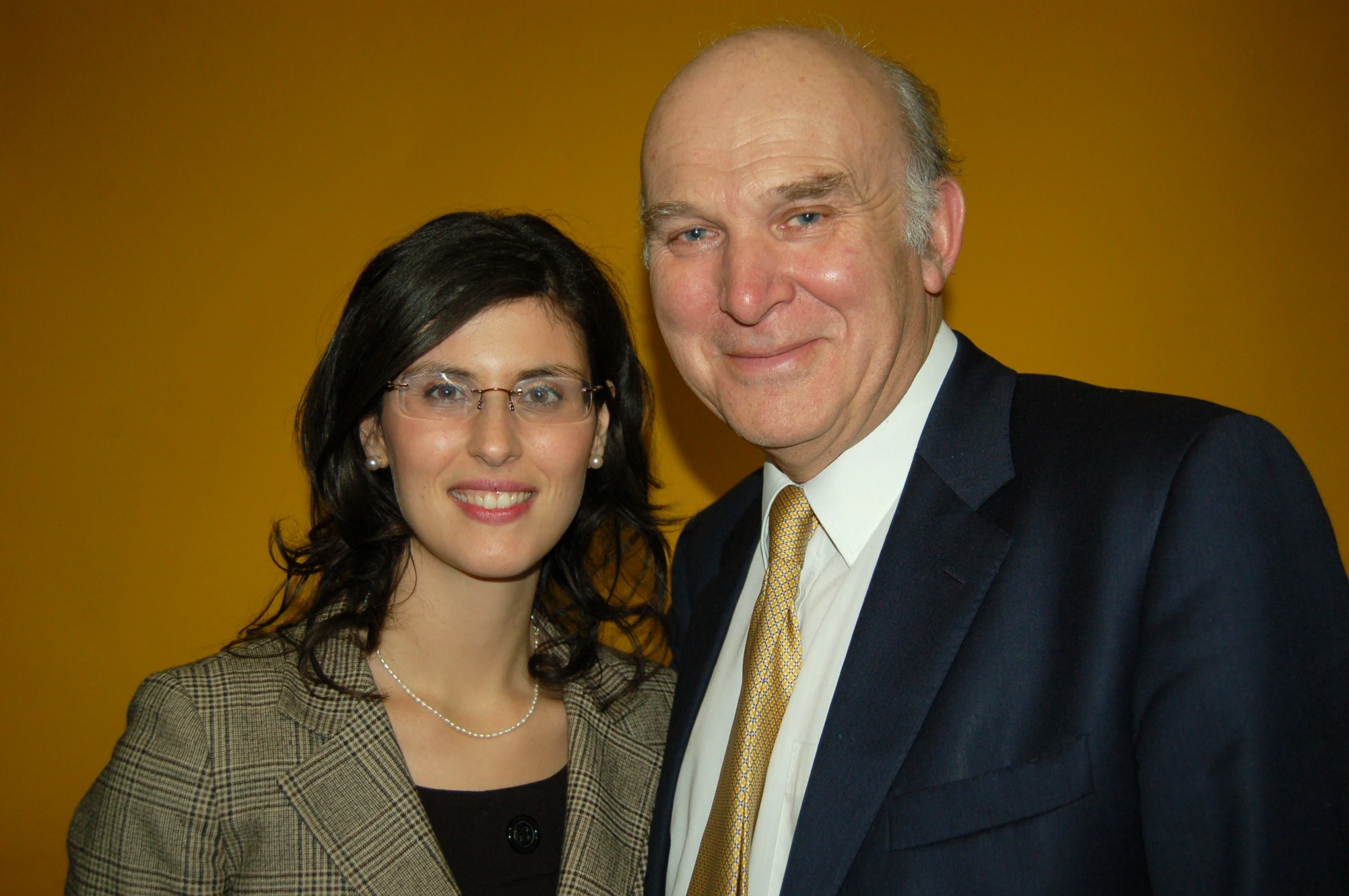 a woman smiling next to a man wearing a suit