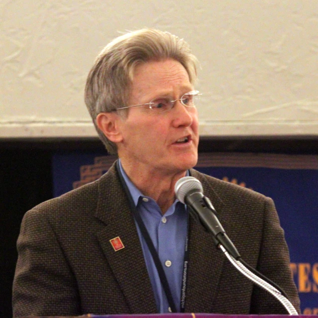 a man with glasses speaking into a microphone