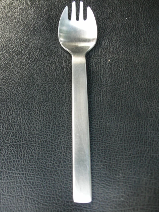 the top of a silver fork on black surface