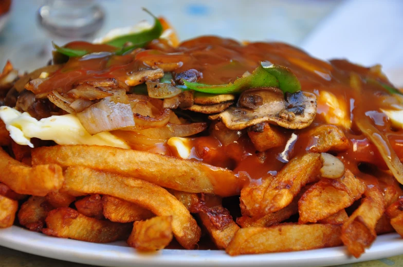 a plate full of french fries covered in some sauce