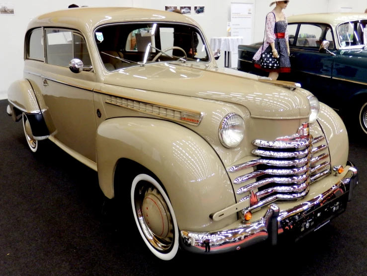 a woman stands next to old cars in a showroom