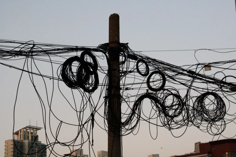 electric wires are tangled up around a telephone pole