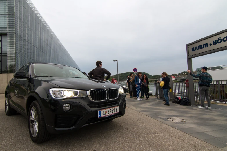 a bmw suv parked next to a car with passengers walking by