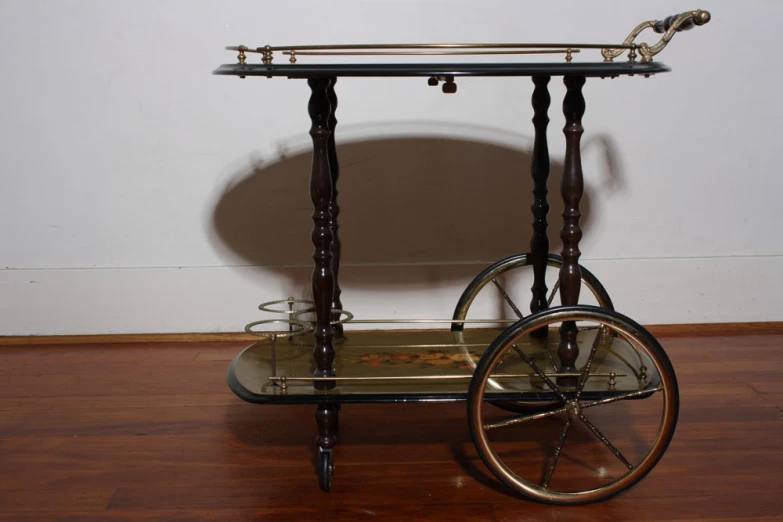 an antique ss and glass serving cart on wheels