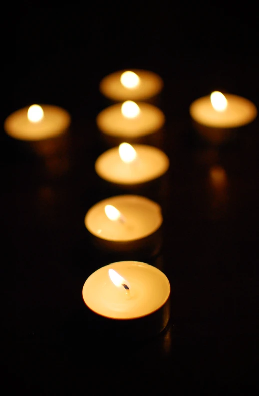 several lit candles sitting on the ground in a row