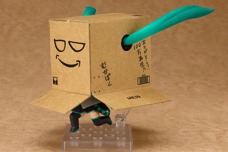 a cardboard box that has been shaped like a man with green plastic eyes and a blue toothbrush in its mouth
