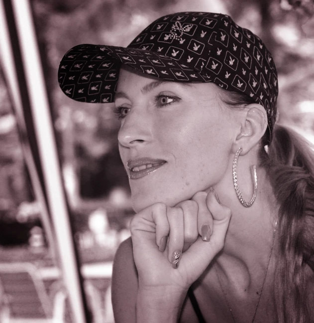 a woman is sitting at a table wearing earrings and a hat