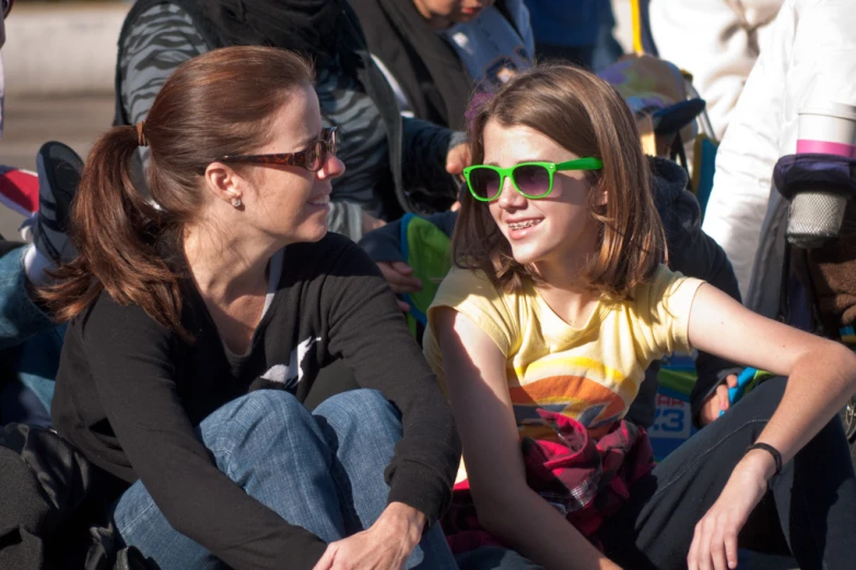 a woman with sunglasses is sitting with a little girl