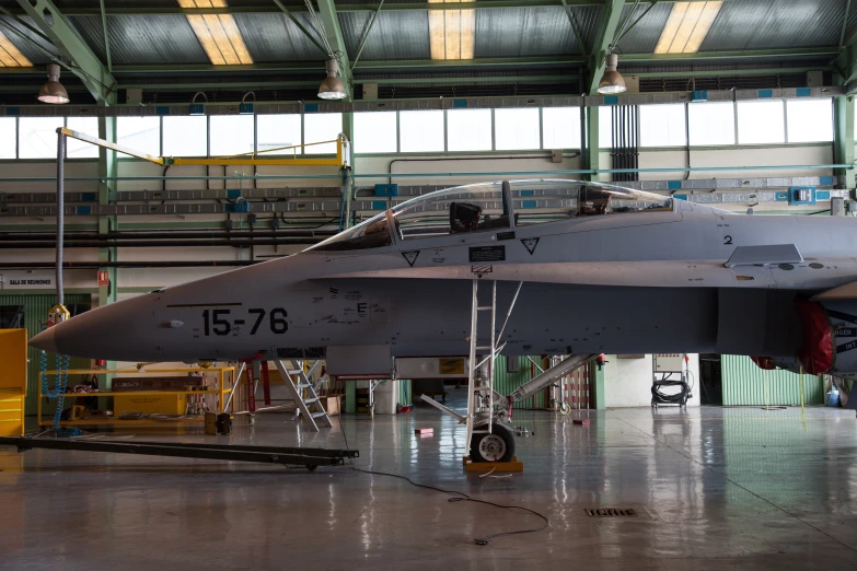 a gray fighter jet in an airplane hangar
