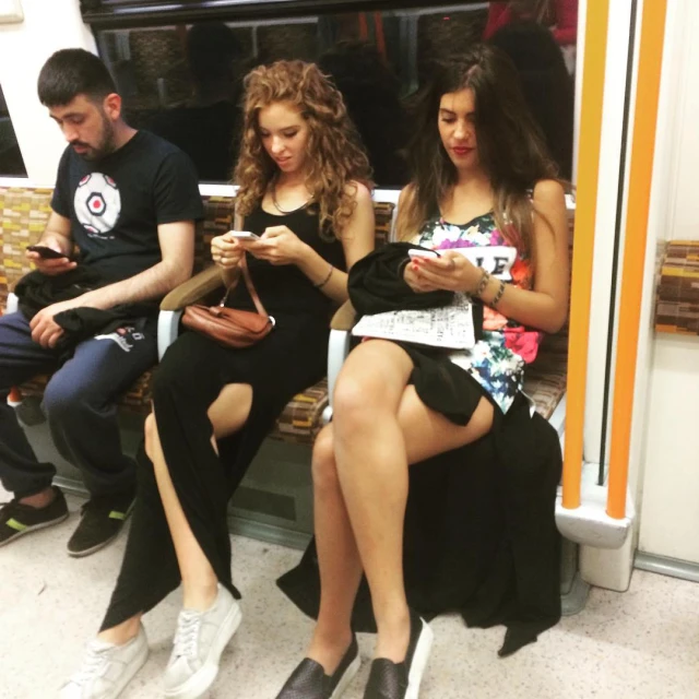 a group of people sitting on a bench with one looking at their cell phone